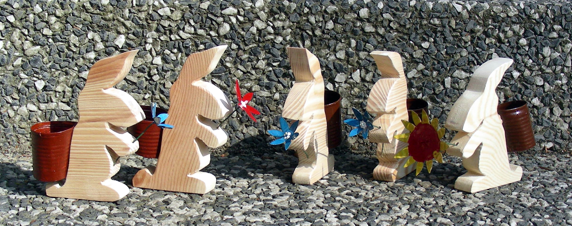 Kleine Holzosterhasen mit Kiepe auf dem Ruecken und einer Blume in der Pfote, Made by Dr. Scheibe